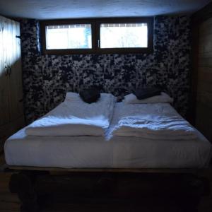 a bed in a room with two windows at Apartman Dunja -Ski skola in Kopaonik