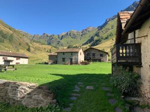 a building with a green field and mountains in the background at Baita Mirellina - Case di Viso in Ponte di Legno