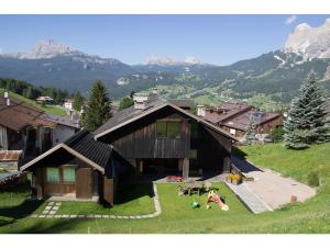 a house on a hill with people laying on the grass at Cristallo & Faloria Suite Apartments in Cortina dʼAmpezzo