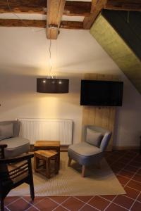 ein Wohnzimmer mit 2 Stühlen und einem Flachbild-TV in der Unterkunft Magdalenenhof am Huywald - Kornboden mit Aussicht in Dingelstedt