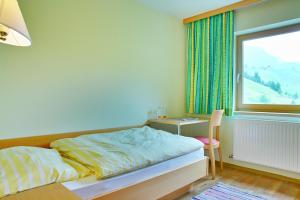 um quarto com uma cama, uma secretária e uma janela em Der Lecher em Lech am Arlberg