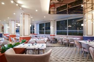 a restaurant with tables and chairs and windows at Amari Don Muang Airport Bangkok in Bangkok