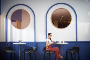 a woman sitting on a chair in a room with two mirrors at Amari Don Muang Airport Bangkok in Bangkok