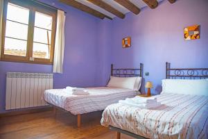 two beds in a room with purple walls at Casa Pirinea Ordesa in Belsierre +60 photos