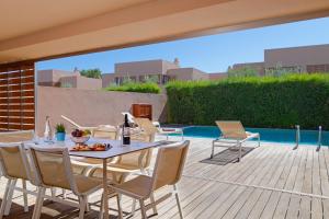 een patio met een tafel en stoelen naast een zwembad bij Salgados Beach Villas in Albufeira