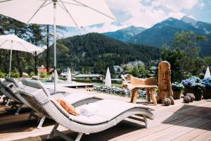 a patio with chairs and a pool with mountains in the background at Alpin Resort Sacher in Seefeld in Tirol