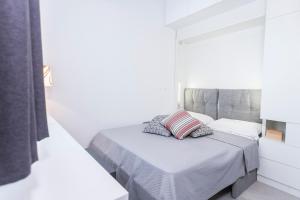 1 dormitorio blanco con 1 cama con 2 almohadas en Apartman Amore, en Baška Voda