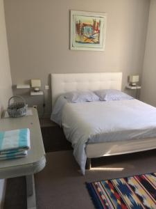 1 dormitorio con cama blanca y mesa en Chambre d'Hôtes Le Moulin, en Bessines