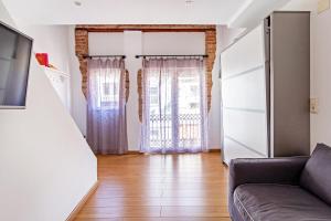 ein Wohnzimmer mit einem Sofa und 2 Fenstern in der Unterkunft Apartamento con terraza cerca de la playa in Valencia