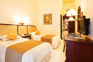 a hotel room with two beds and a flat screen tv at Puri Asri Hotel & Resort in Magelang