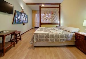 a bedroom with a bed and a desk and a television at Guest House Rakovina in Sozopol