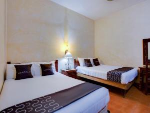a hotel room with two beds and two lamps at Hotel Valle De Oaxaca in Oaxaca City