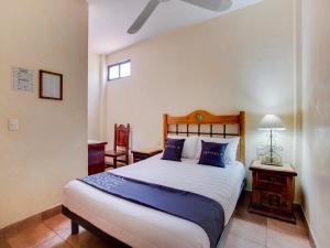 a bedroom with a large bed with blue pillows at Hotel Valle De Oaxaca in Oaxaca City
