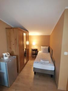 a small bedroom with a bed and a small refrigerator at W Starym Ogrodnictwie in Przyszowice