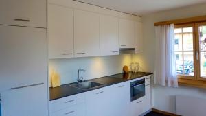 a kitchen with white cabinets and a sink and a window at Ferienhaus Kuster in Sedrun