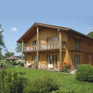 a large wooden house with a balcony and a yard at Niederauer Hof in Neubeuern