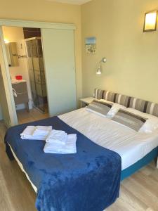 1 dormitorio con 1 cama grande y toallas. en Hôtel Le Plaisance, en Mimizan-Plage