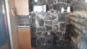 a stone wall with a stove in a kitchen at Cabin at Huskies Farm in Inari