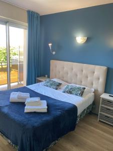 Un dormitorio azul con una cama con toallas. en Hôtel Le Plaisance, en Mimizan-Plage