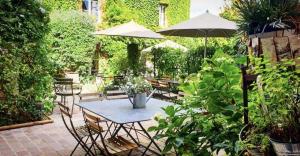 une terrasse avec une table, des chaises et des parasols dans l'établissement La Cour Sainte Catherine demeure de charme, à Honfleur