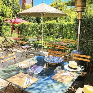 a table with an umbrella and some tables and chairs at La Cour Sainte Catherine demeure de charme in Honfleur