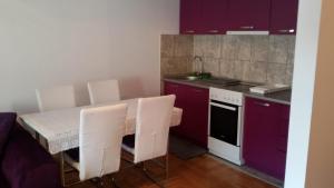 a kitchen with purple cabinets and a table with white chairs at Lili in Arandelovac