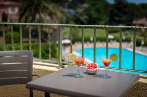 サント・マキシムにあるホテル レ ジャルダン ドゥ サント マキシムのカクテル2杯とフルーツ1杯付きのテーブル