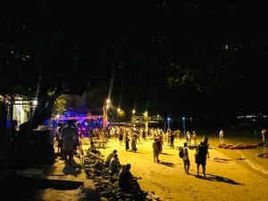 uma multidão de pessoas caminhando em uma praia à noite em Dee Dee Sea Front em Phi Phi Don