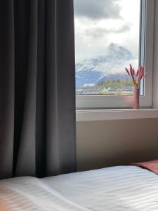 a bedroom window with a view of a snow covered mountain at Frichs Ekspress Åndalsnes in Åndalsnes