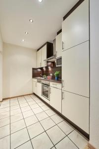cocina con armarios blancos y suelo de baldosa en Haus Seemuschel _ Fewo 2 en Cuxhaven