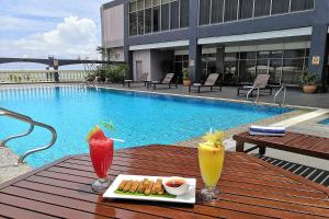 einen Tisch mit 2 Getränken und ein Tablett mit Speisen in der Unterkunft Hotel Grand Continental Kuala Terengganu in Kuala Terengganu