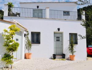 une maison blanche avec des plantes devant elle dans l'établissement La Pluma, à Iznájar