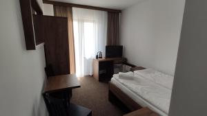 a hotel room with a bed and a television at WILLA ELITA in Krynica Morska
