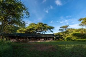 ein Gebäude mit einem grünen Dach auf einem Feld in der Unterkunft Serengeti Woodlands Camp in Serengeti-Savanne