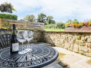 a table with two glasses and a bottle of wine at Swan Cottage in Fearby