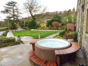 a hot tub sitting on a wooden bench in a yard at Old Hall Cottage in Settle