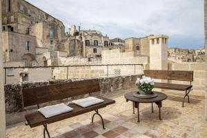 un balcone con 2 panche e un tavolo con fiori di L'Artiere Dimore nei Sassi a Matera