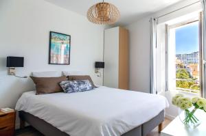 een slaapkamer met een wit bed en een raam bij Totolulu Cannes Smart in Cannes