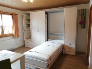 Habitación con cama, armarios y mesa. en Ferienwohnung Casa Ursina en Sedrun