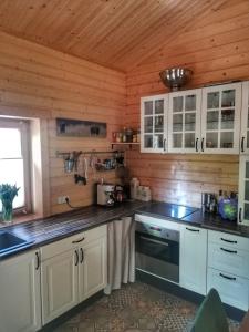 eine Küche mit weißen Schränken und einer Holzwand in der Unterkunft Blockbohlenhaus bei Potsdam in Schwielowsee