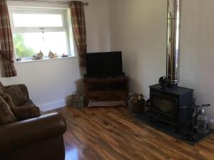 a living room with a fireplace and a television at Grooms cottage in Thornton