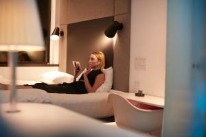 a woman sitting on a bed reading a book at citizenM Schiphol Airport in Schiphol