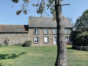 une vieille maison en pierre avec un arbre en face de celle-ci dans l'établissement Domaine de l'Aumône, à Cherrueix