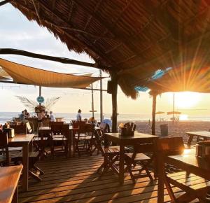 un restaurante en la playa con mesas y sombrillas en Hotel El Delfin, en Monterrico