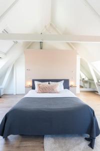 a bedroom with a large bed with a blue blanket at Gravenstraat in Den Burg