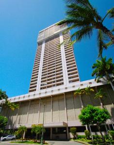 a tall building with a palm tree in front of it at Royal Kuhio Resort in Honolulu