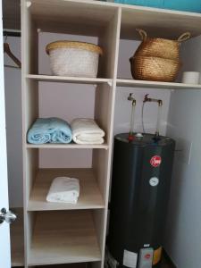 a book shelf with a refrigerator and towels at Departamento Un Ambiente Centro de Concepción in Concepción