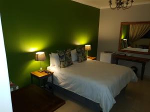 a bedroom with a bed with a green wall at Poetry Guestrooms in Vryburg