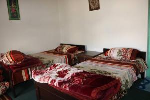 een kamer met 3 bedden en een stoel bij Fort View Guest House in Baltit