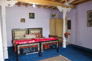 a bedroom with a bed with a red bedspread at Fort View Guest House in Baltit